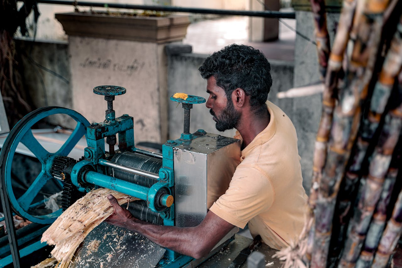 Services South Asian man using traditional machine to extract fresh sugarcane juice in Chennai.