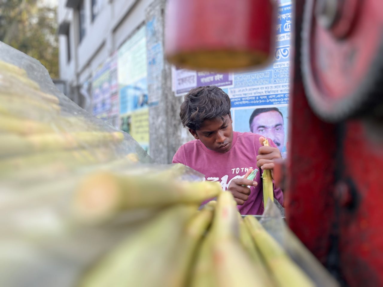 About A young man skillfully preparing sugarcane juice at a street stall, highlighting urban lifestyle.
